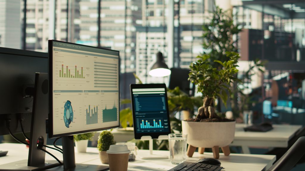 Monitores com painéis de análise de custos de cloud sobre uma mesa de escritório